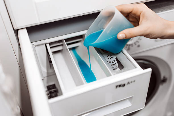 istock Hand pouring blue liquid detergent into washing machine compartment 2253185540