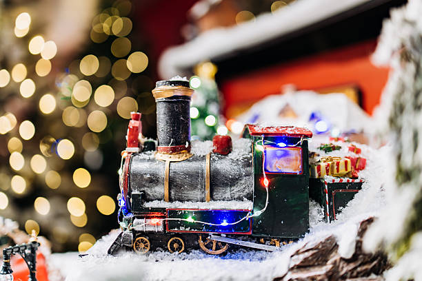 istock Miniature Christmas train set with festive decorations, surrounded by snow-covered trees 2253185908