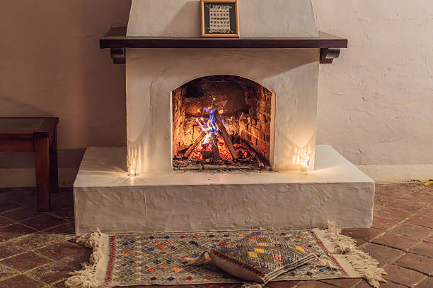 istock A warm and inviting scene featuring a lit fireplace with glowing firewood and candles. A colorful traditional rug and pillow lie on the floor, creating a cozy atmosphere. Home, relaxation, and rustic comfort concept 2253186171