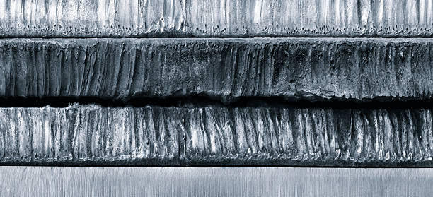 Stack of  thick heavy metal plates rusty uneven surface after laser cutting. plates stacked top each other, creating sense depth and texture. scene is somewhat dark industrial  background