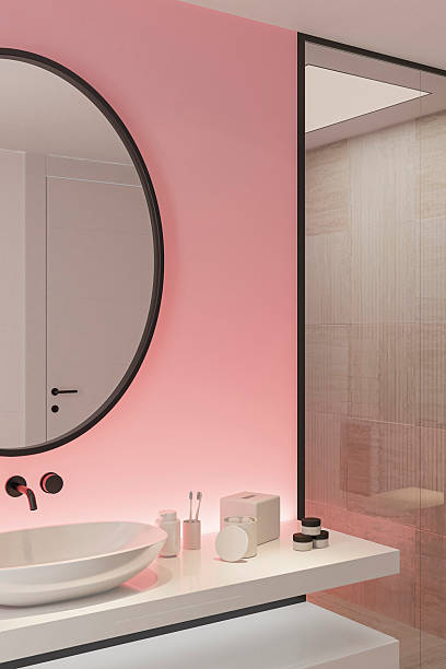 istock Stylish Bathroom with Pink Accent Back Lit Wall and Round Mirror 2253188137