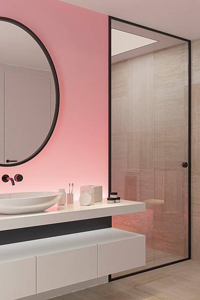 istock Stylish Bathroom with Pink Accent Back Lit Wall and Round Mirror 2253188149