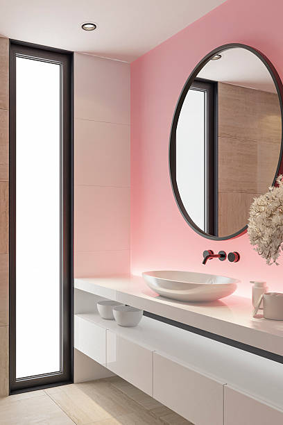 istock Stylish Bathroom with Pink Accent Back Lit Wall and Round Mirror 2253188170