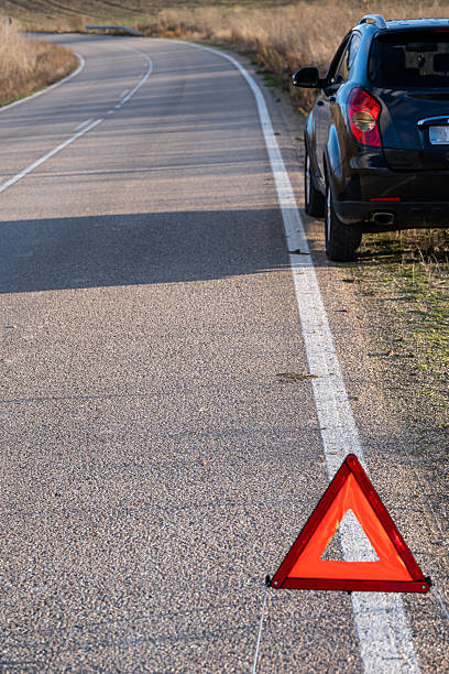 istock Driver placing a warning triangle on the shoulder of the road with a broken-down vehicle, emergency signal, and warning triangle. 2253189047