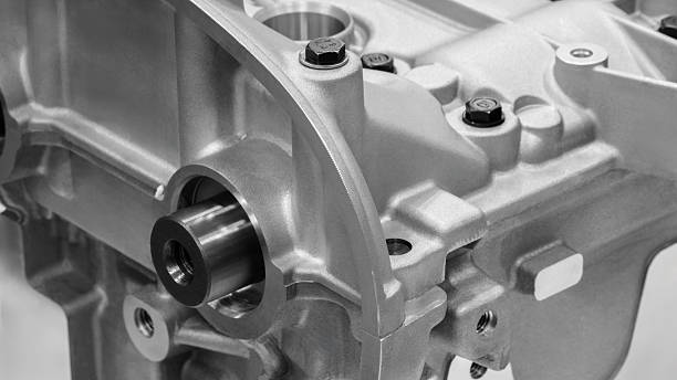 An intricate engine component is positioned prominently, highlighting its polished surface and complex design in a well-lit workshop environment.