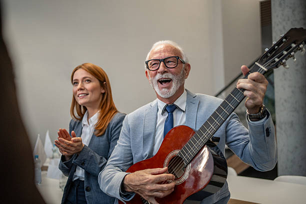 istock Senior businessman playing guitar at office party 2253191185