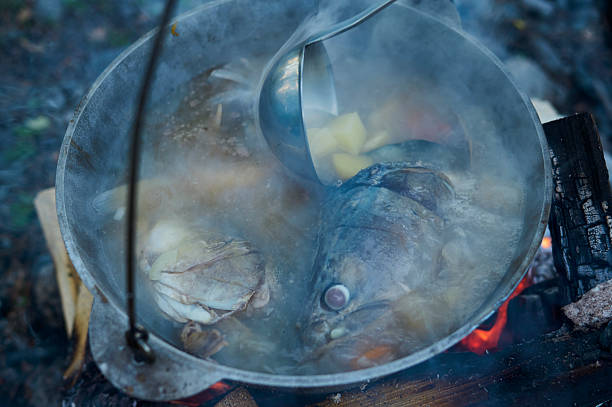 Cooking fish soup in the stowed bowler over a campfire