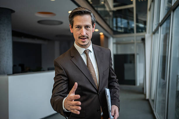 Male professional extending an open hand for a handshake, symbolizing partnership, greeting, agreement, or a warm welcome in a contemporary corporate setting