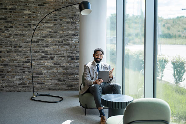 istock Businessman using digital tablet while sitting on chair in modern office 2253195938