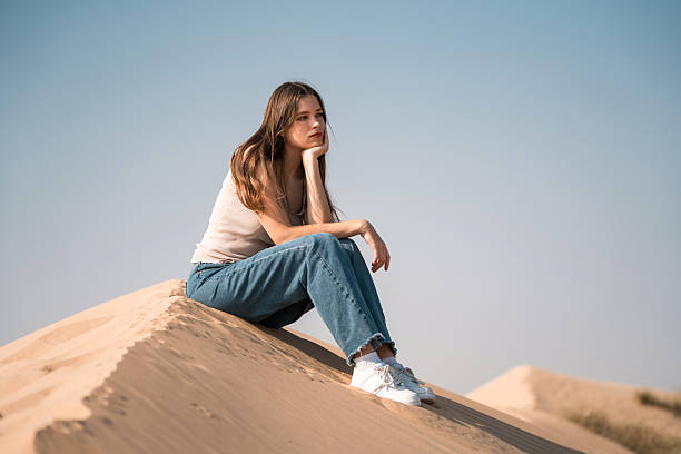 istock Young Woman Relaxing in Dubai Desert Under Bright Sunlight 2253196493