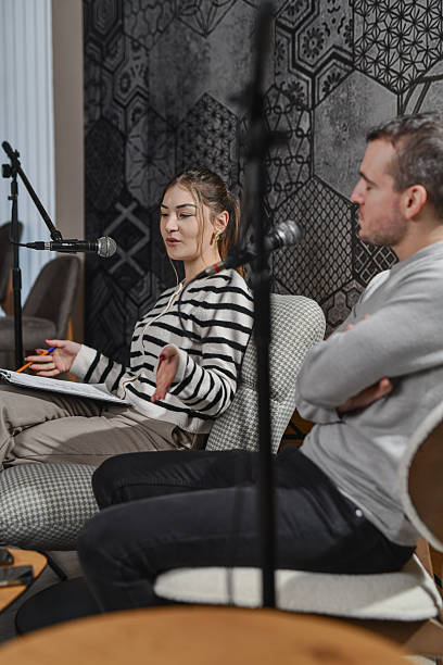 istock Female Host Interviewing Guest On Stage With Microphones In A Studio Talk Show 2253199743