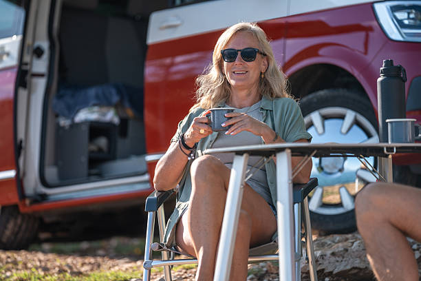 istock Content Camper Sips Fresh Coffee While Relaxing Near Ocean Campsite 2253201036