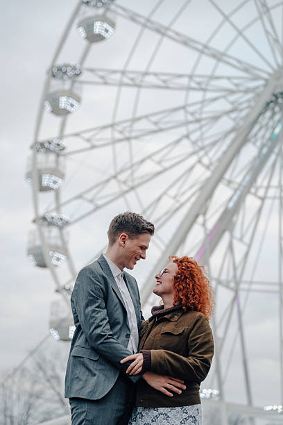 istock Couple smiling and embracing at amusement park 2253203500