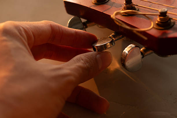 istock Hand tuning an acoustic guitar pegs before a musical performance 2253206182