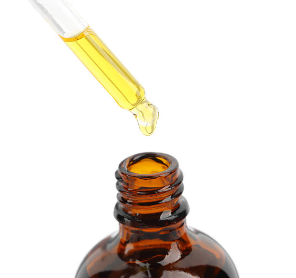 istock Dripping tincture from pipette into bottle isolated on white 2253207814