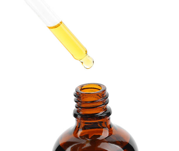 istock Dripping tincture from pipette into bottle isolated on white 2253207826