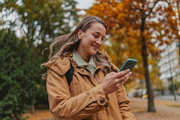 istock Woman smiling while using a smartphone in Berlin park during autumn 2253209740