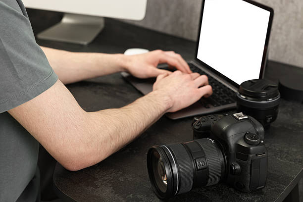 istock Photographer using laptop at dark table with camera, closeup 2253212401
