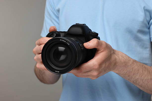 istock Photographer holding camera on grey background, closeup 2253212408