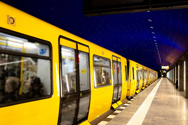 Modern yellow metro train standing at an underground station platform in Berlin.