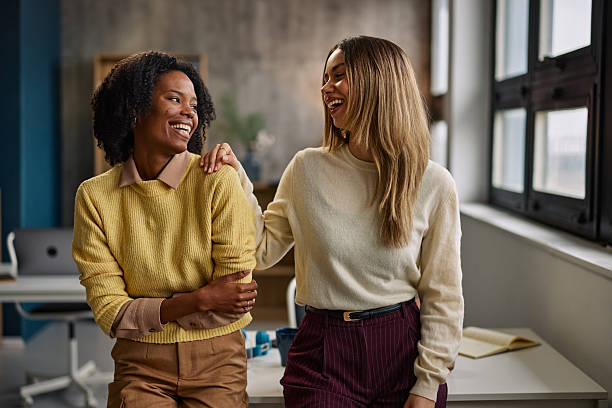 istock Two friends share a laugh in a bright office, showcasing teamwork and friendly collaboration. 2253215895