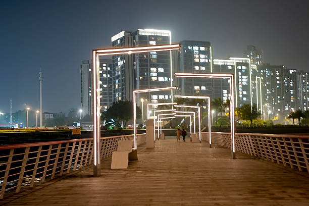 People strolling under the geometric light corridor at night