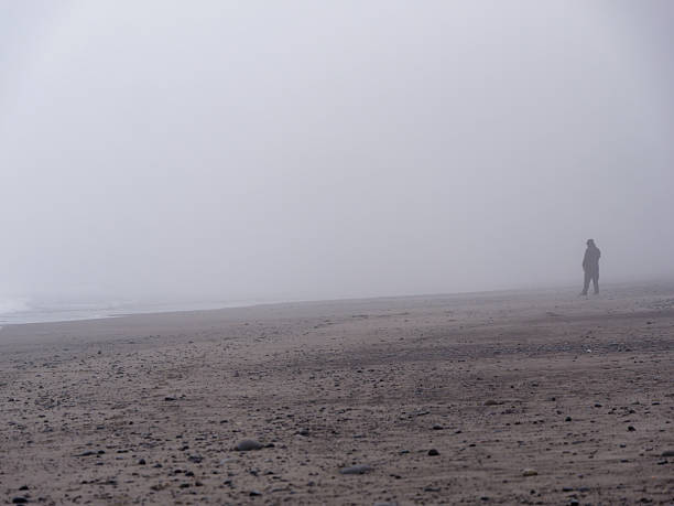 Lone silhouette walking through thick fog on the beach at Ruby Beach, Olympic National Park, Washington State, USA