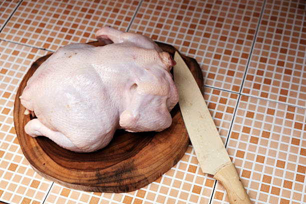 Fresh Raw uncooked whole chicken with knife on a wooden chopping board, preparation cooking.