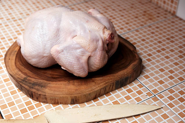 Fresh whole chickens displayed for sale in traditional butcher shop poultry section.