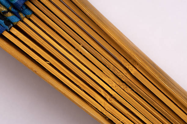 Macro shot of bamboo fan ribs in folded state on a light background, bamboo texture