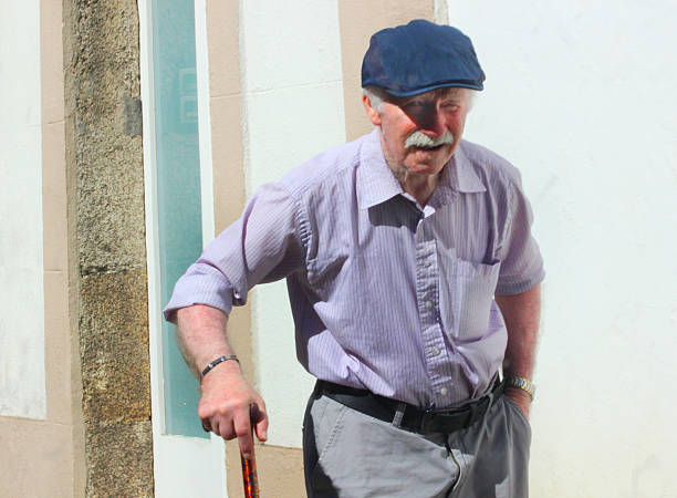 Senior man walking with walking cane along sidewalk a sunny afternoon. A Coruña , Galicia, Spain