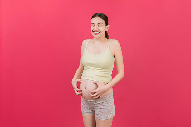 istock Pregnant woman scratching her belly on colored background 2253231040