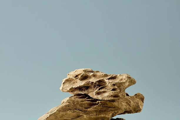 Natural stone pedestal stack for product display against a blue background.