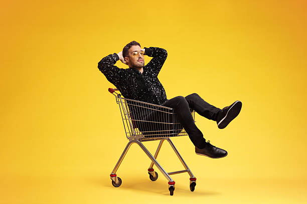istock Man in a sequin bomber jacket sitting inside a shopping cart 2253232669