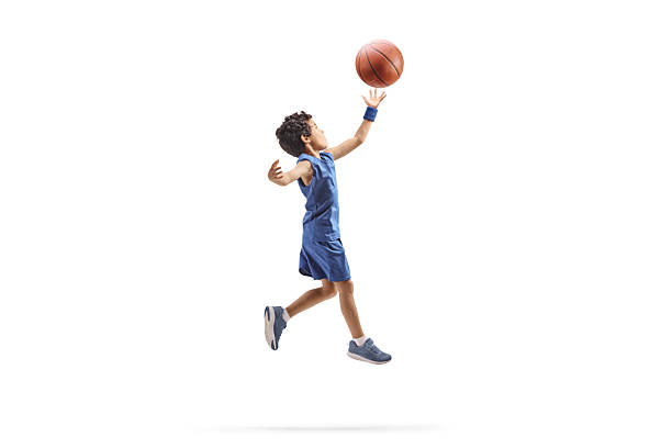 Young male athlete jumping high, scoring a point by performing a slam dunk during basketball practice