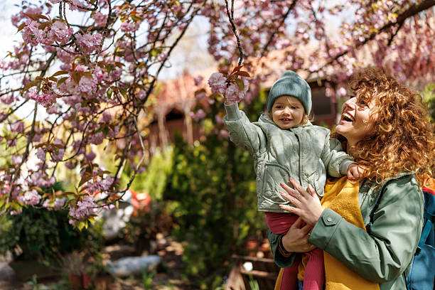 Devoted mother teaches daughter about trees blooming in spring nature