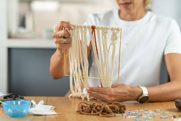 Woman crafting tapestry in a small home workspace. Captures creative focus, material control, and gentle artistic flow.