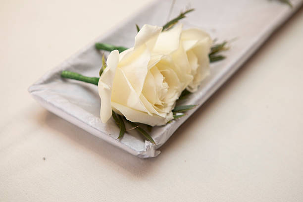 White-coloured rose buttonhole flowers on a tray - delivered before a wedding
