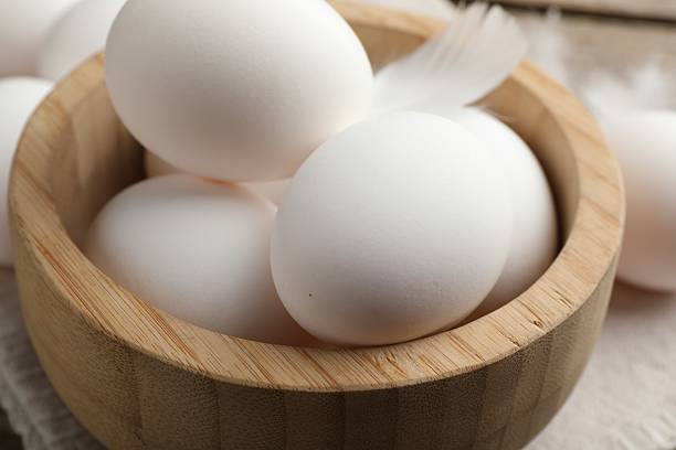 Raw chicken eggs in bowl on table, closeup