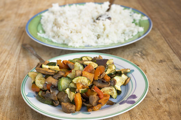 healthy ratatouille with sauteed zucchini peppers mushrooms and vegetables served with white basmati rice for nutritious vegetarian meal on rustic table