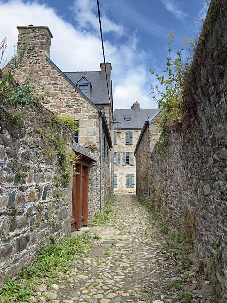 Vertical townscape of an ancient stone-walled alley leading to old, three storeyed traditional houses in the historic town of Treguier, Brittany, France