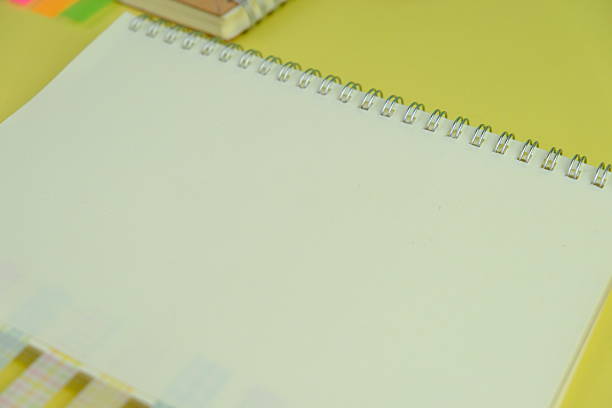 Open blank spiral notebook with black pencil on yellow background. Empty Space for your text. business and education concept