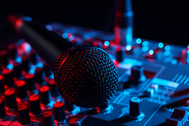 istock Professional mixing console with microphone on black background in neon lights, closeup 2253252075