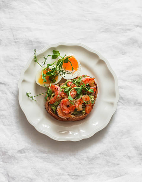 istock Delicious breakfast, brunch, tapas, snack - boiled egg and avocado, shrimp sandwich on a light background, top view 2253252710