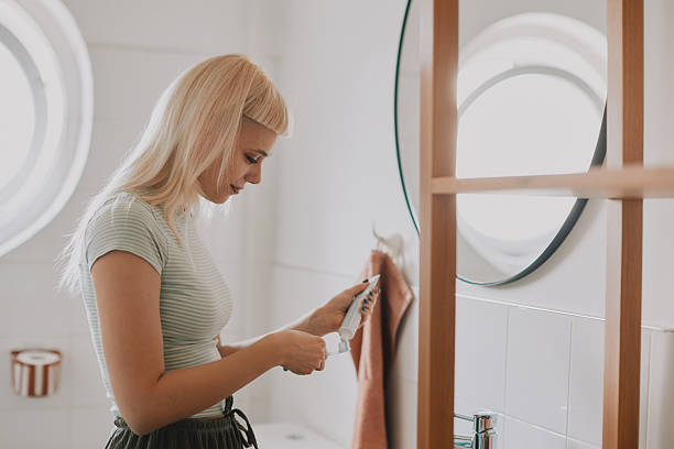 istock Young Hipster Woman Brushing Teeth in Bathroom, Morning Routine, Looking in Mirror 2253255321