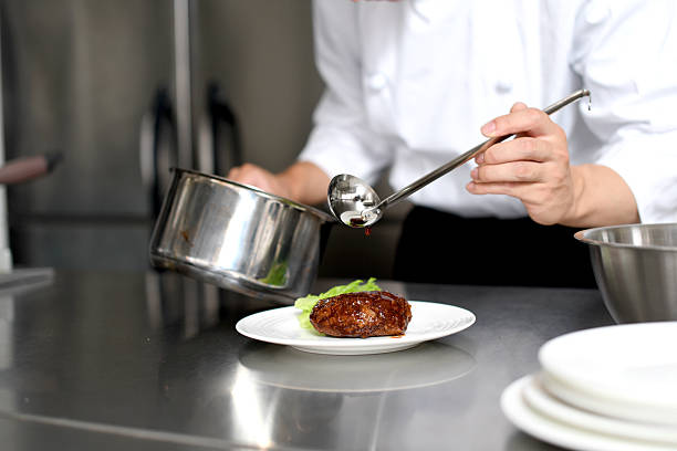 Professional chef carefully plating a gourmet dish in a restaurant kitchen. High-end cuisine with fresh ingredients, precision, and artistic presentation