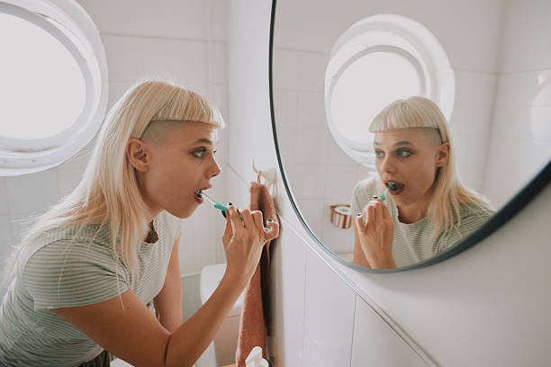 istock Young Hipster Woman Brushing Teeth in Bathroom, Morning Routine, Looking in Mirror 2253256646