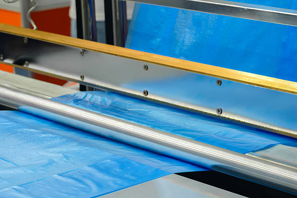 istock Automatic polyethylene plastic bag production machine with lighting effect. Close-up of the roller of the plastic bag production machine in the light blue scene. product packaging concept 2253257405