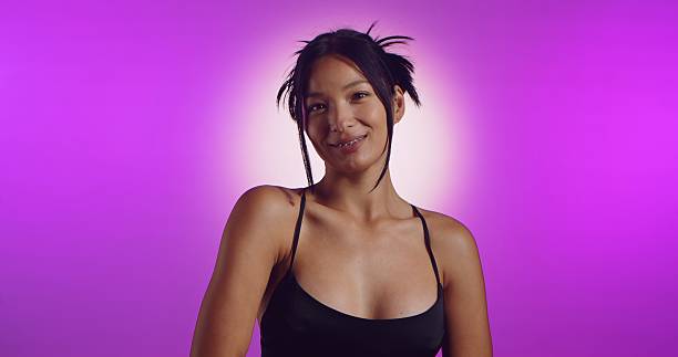 A young Korean model poses in a studio lit by pink neon lights. The concept is beauty, fashion and natural feminine beauty.