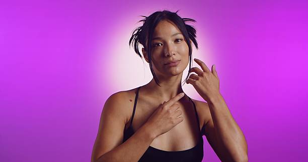 A young Korean model poses in a studio lit by pink neon lights. The concept is beauty, fashion and natural feminine beauty.